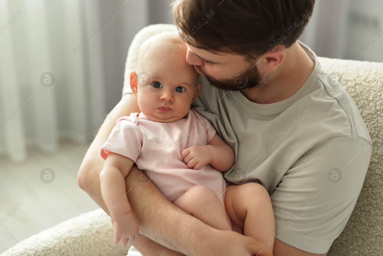 Photo of Father kissing his cute baby in armchair at home