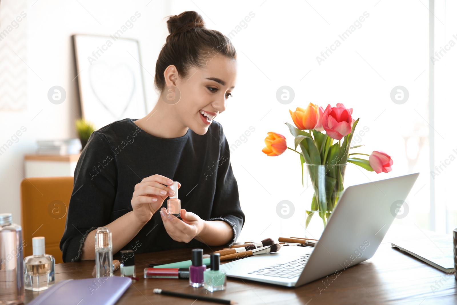 Photo of Young blogger with laptop and different cosmetics at table