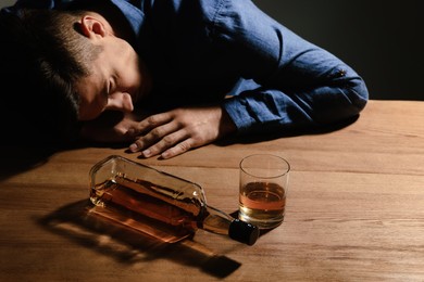 Photo of Addicted man with alcoholic drink at wooden table