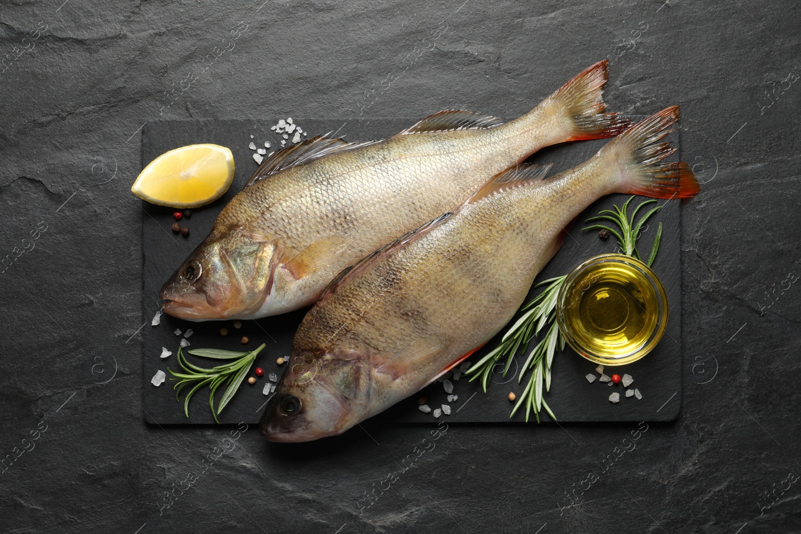 Photo of Fresh raw perches and ingredients on black slate table, top view. River fish