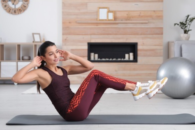 Photo of Young woman in fitness clothes doing exercise at home. Space for text