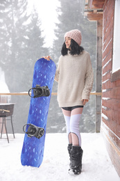 Photo of Young woman with snowboard wearing winter sport clothes outdoors