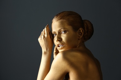 Portrait of beautiful lady with gold paint on skin against grey background