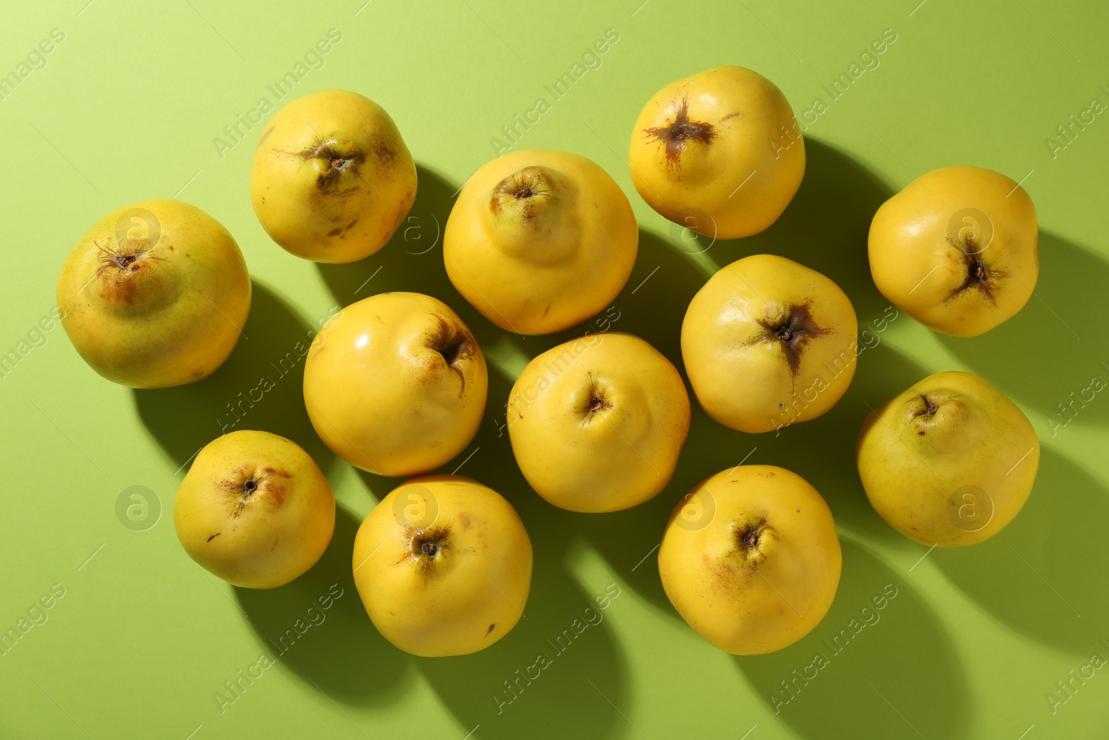 Photo of Tasty ripe quinces on light green background, flat lay