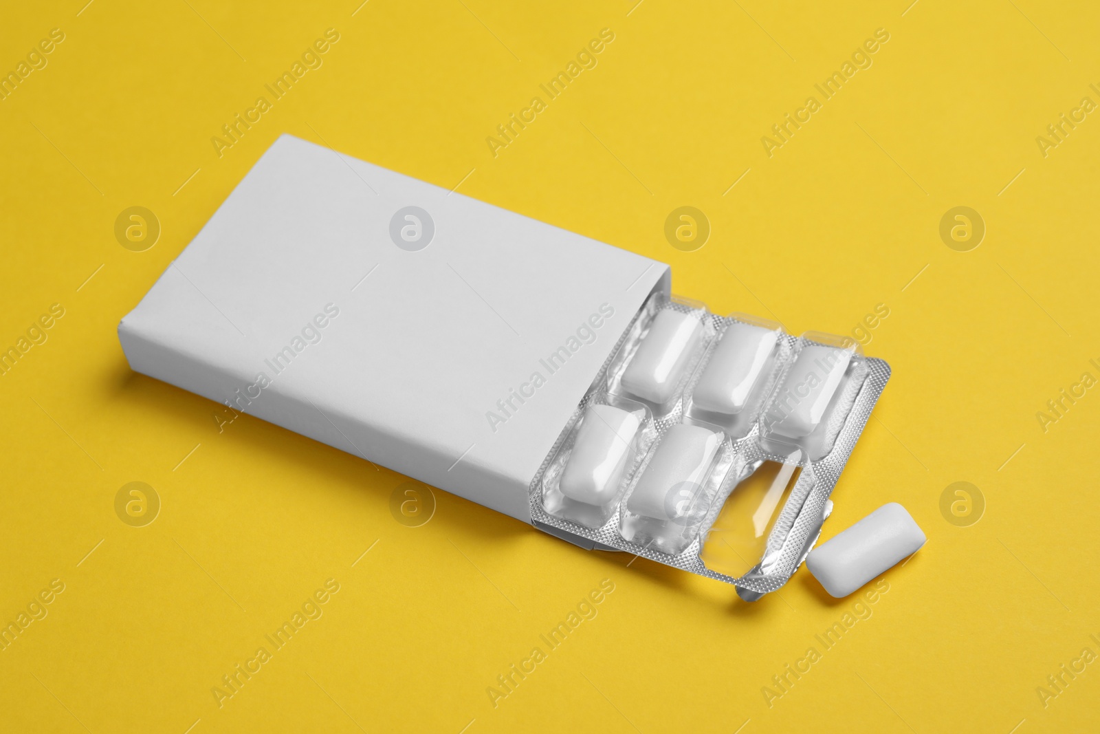 Photo of Pack with tasty chewing gums on yellow background