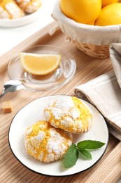 Photo of Tasty homemade lemon cookies with mint and fresh fruits on wooden tray