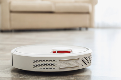 Photo of Modern robotic vacuum cleaner on floor in living room. Space for text