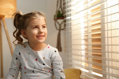 Portrait of cute little girl near window at home