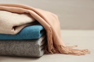 Stack of cashmere clothes on wooden table, closeup