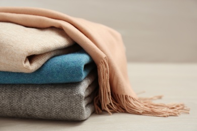 Photo of Stack of cashmere clothes on wooden table, closeup