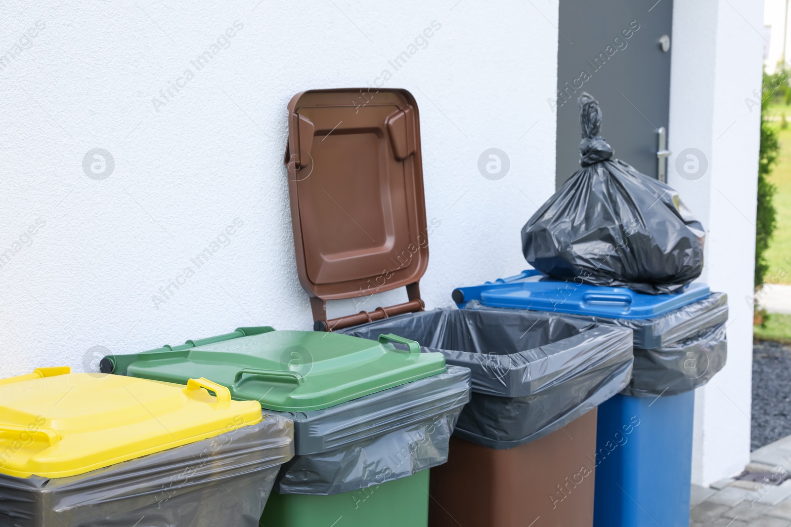 Photo of Plastic bag with garbage and recycling bins outdoors. Waste sorting