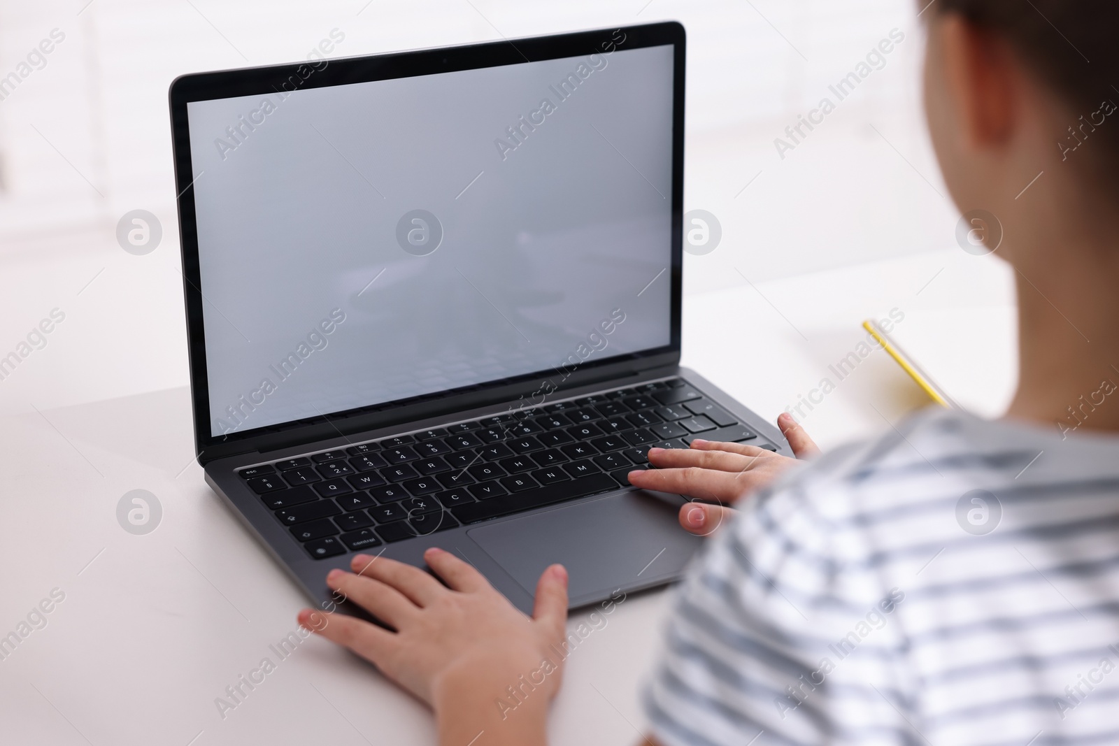 Photo of E-learning. Girl using laptop during online lesson at table indoors, closeup