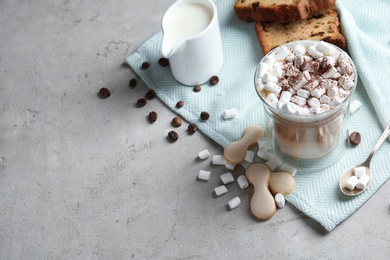 Composition with glass of delicious coffee drink and different sweets on grey table. Space for text