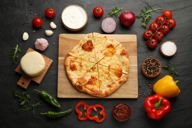 Photo of Delicious khachapuri with cheese surrounded by different products on black table, flat lay