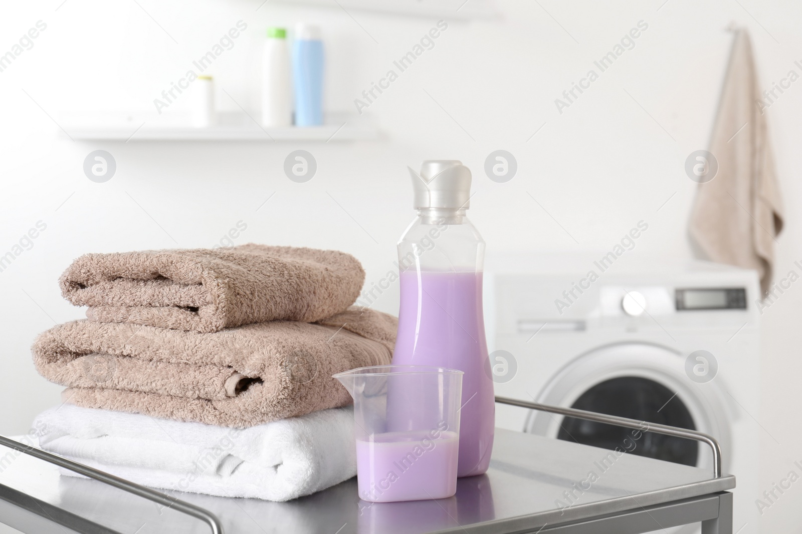 Photo of Stack of clean towels and detergent on table in laundry room. space for text