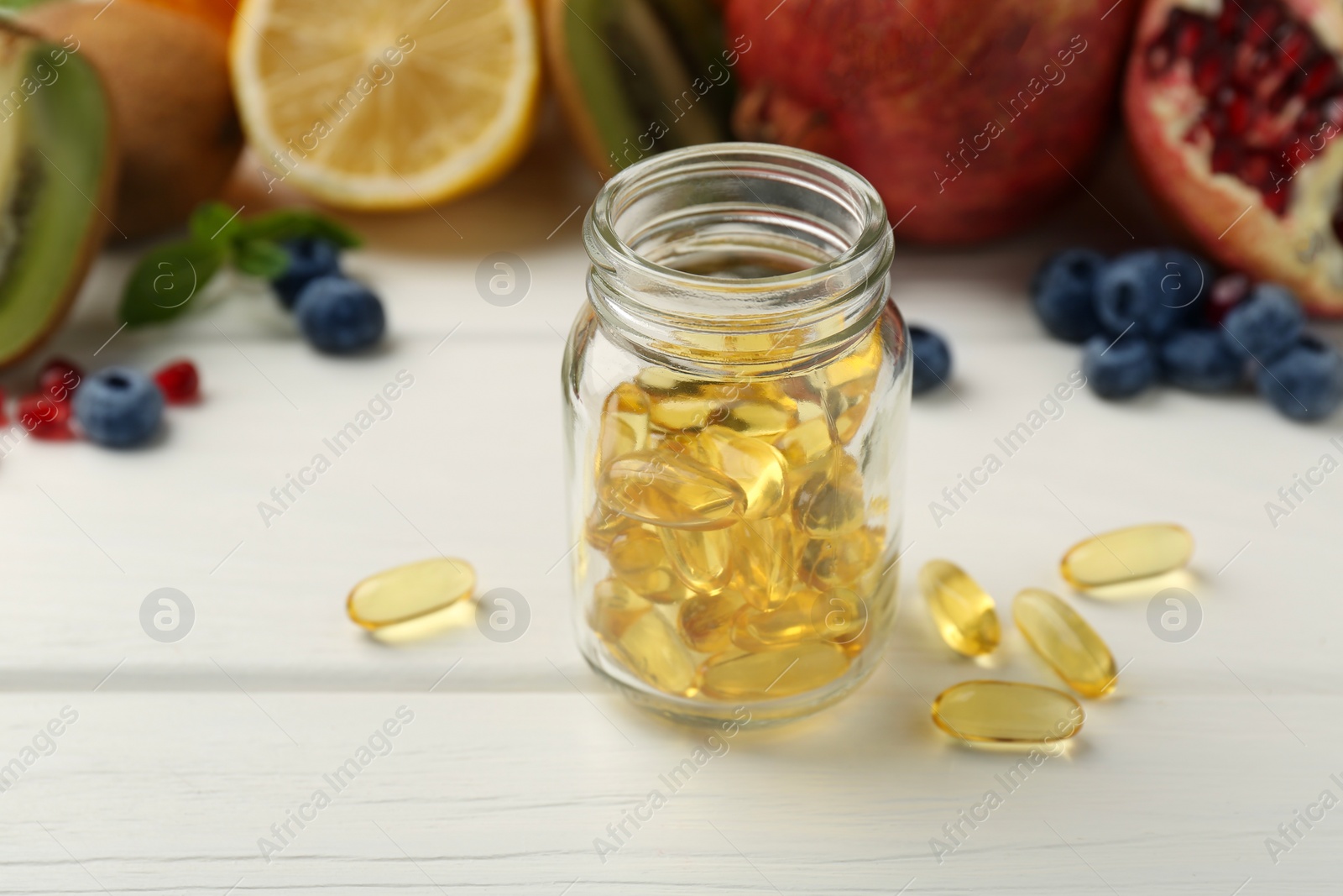 Photo of Vitamin pills in bottle and fresh fruits on white wooden table