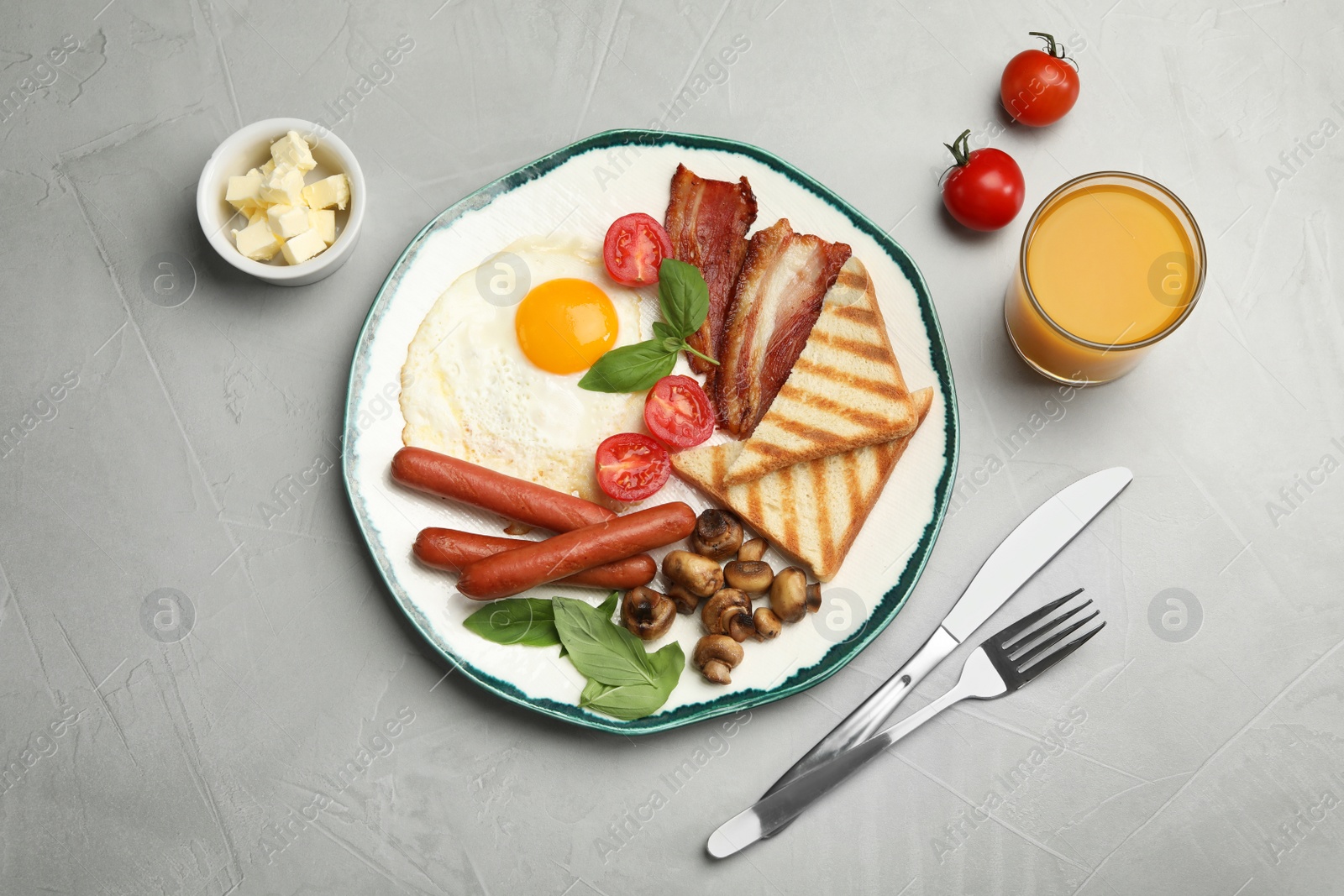 Photo of Traditional English breakfast with fried egg served on grey table, flat lay