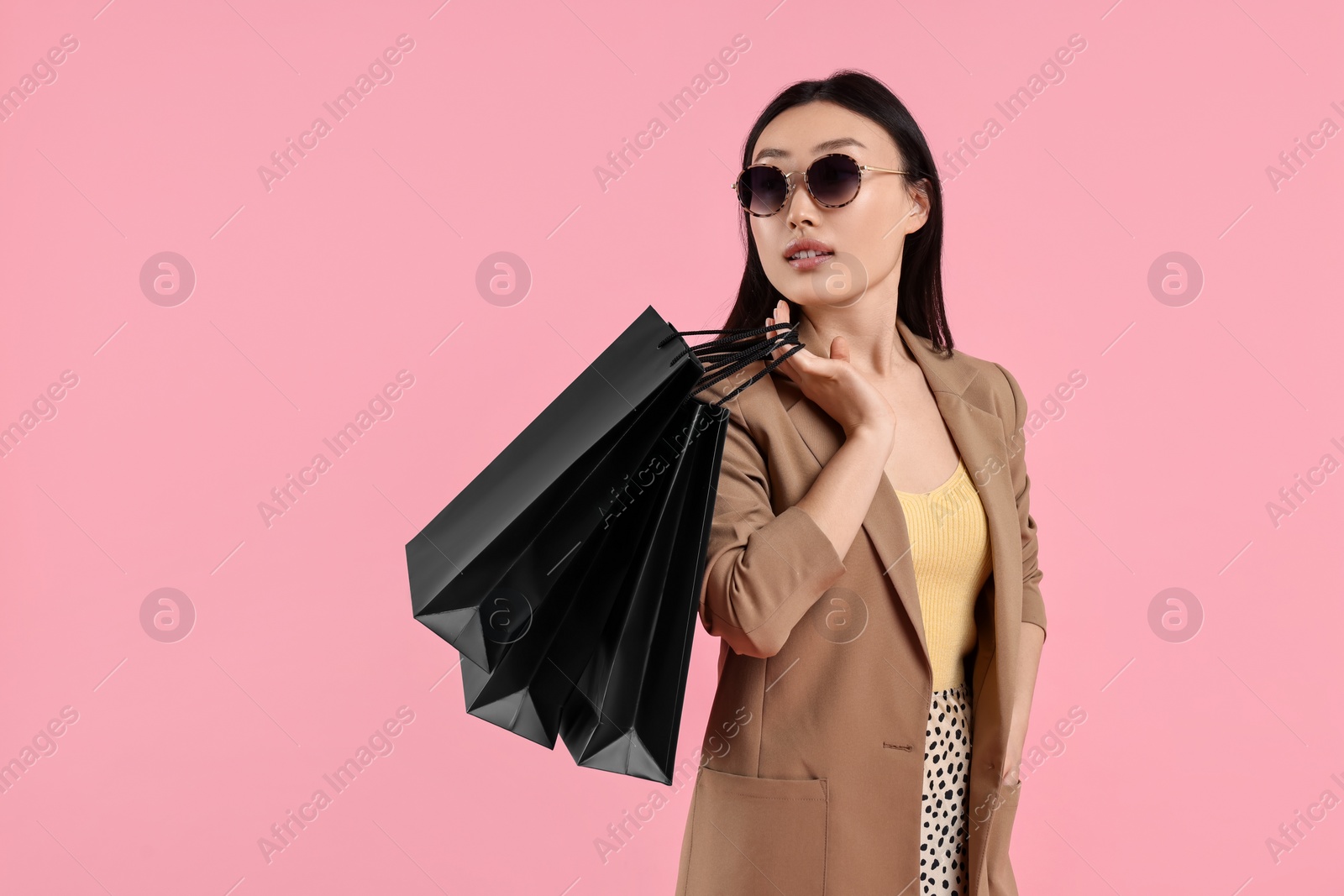 Photo of Beautiful woman with shopping bags on pink background. Space for text