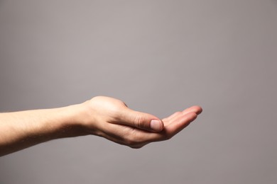 Photo of Man holding something in hand on grey background, closeup. Space for text