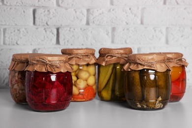 Photo of Many glass jars with different preserved vegetables and mushrooms on light grey table