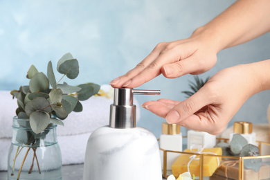 Woman using soap dispenser indoors, closeup view