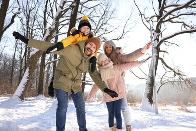 Happy family having fun in sunny snowy forest