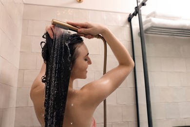 Young woman washing hair while taking shower at home