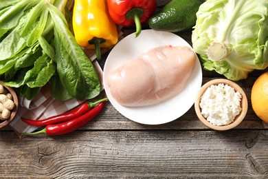 Photo of Healthy meal. Different vegetables and raw chicken breast on wooden table, flat lay