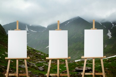 Image of Wooden easels with blank canvases in mountains
