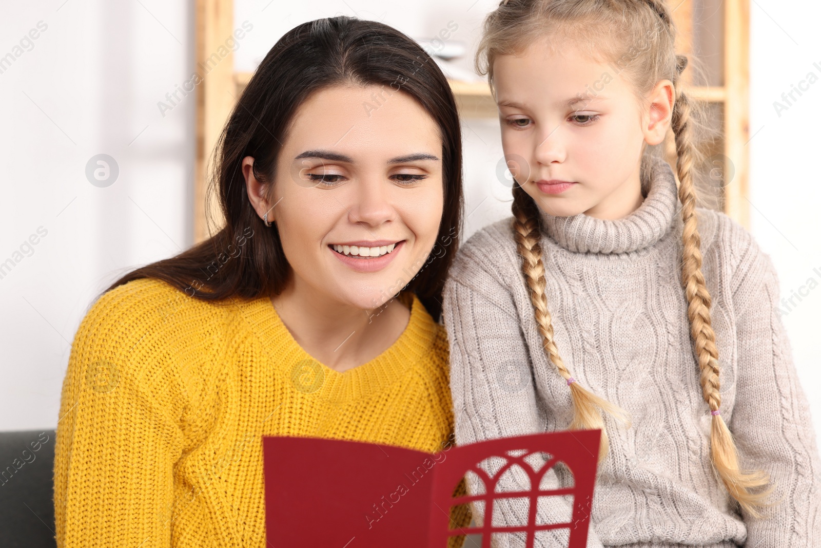 Photo of Happy woman receiving greeting card from her daughter at home