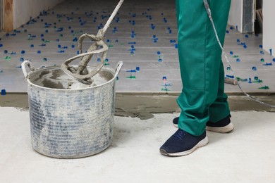 Man mixing tile adhesive indoors, closeup view