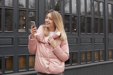 Photo of Beautiful young woman using mobile phone outdoors