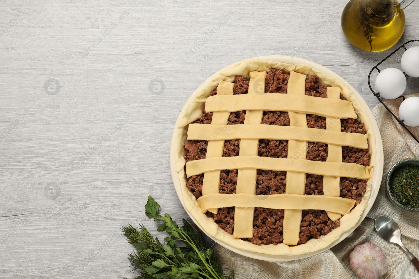 Photo of Raw meat pie and ingredients on white wooden table, flat lay. Space for text