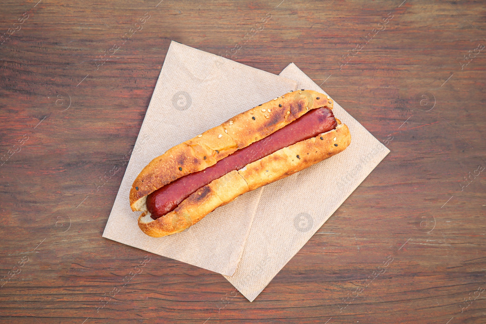 Photo of Fresh tasty hot dog on wooden table, top view