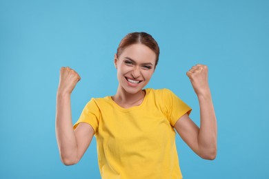 Happy fan celebrating on light blue background