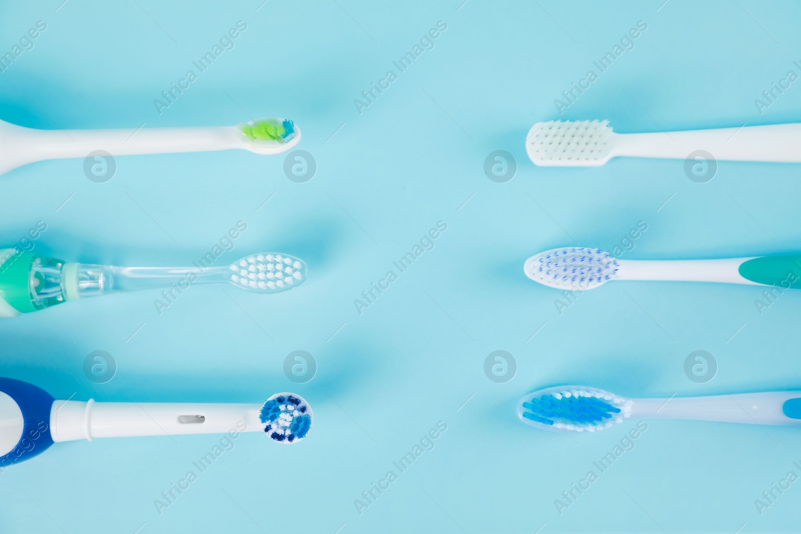 Photo of Electric toothbrushes on light blue background, flat lay