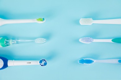 Electric toothbrushes on light blue background, flat lay