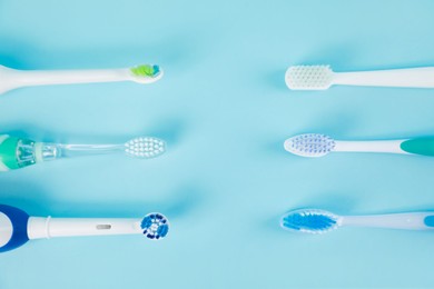 Photo of Electric toothbrushes on light blue background, flat lay