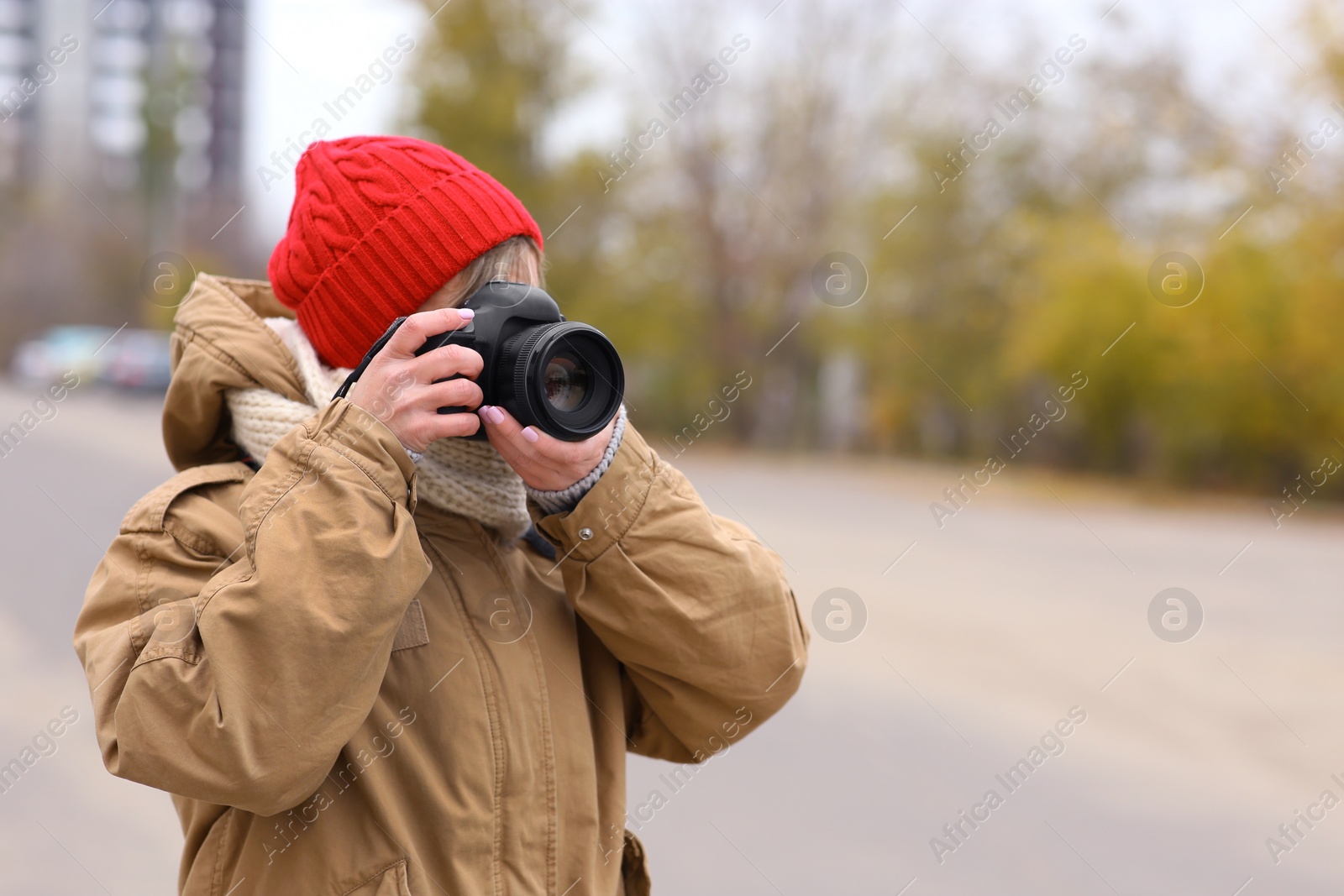 Photo of Photographer taking photo with professional camera outdoors. Space for text