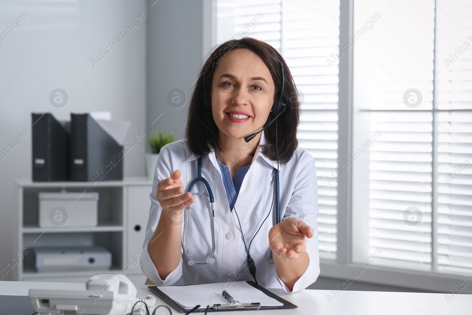 Photo of Doctor with headset at table in office. Hotline service