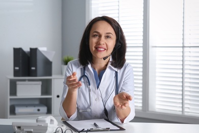 Photo of Doctor with headset at table in office. Hotline service