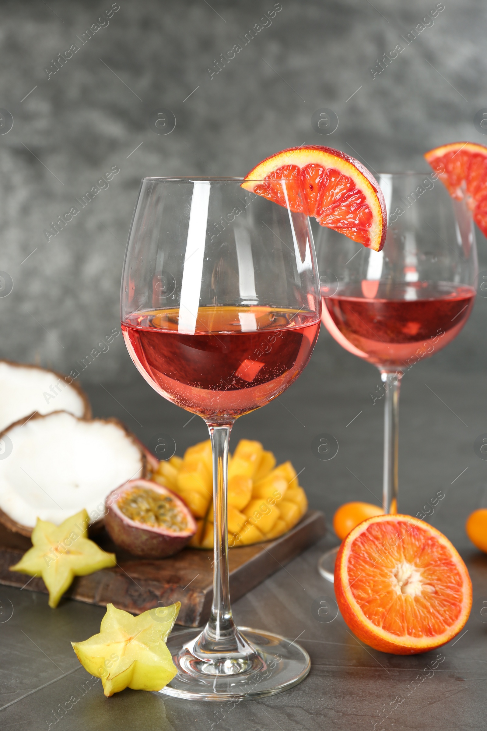 Photo of Delicious exotic fruits and wine on grey table