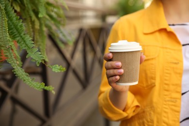 Woman with takeaway coffee cup outdoors, closeup