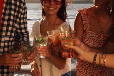 Group of friends with drinks having fun near river at summer party, closeup