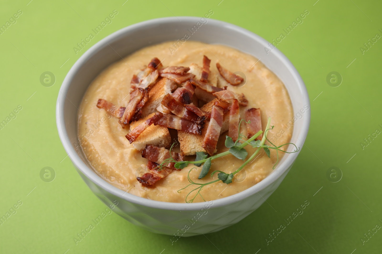 Photo of Delicious lentil soup with bacon and croutons on green background