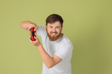 Happy man playing video game with controller on pale green background