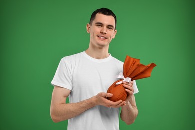 Photo of Easter celebration. Handsome young man with wrapped gift on green background
