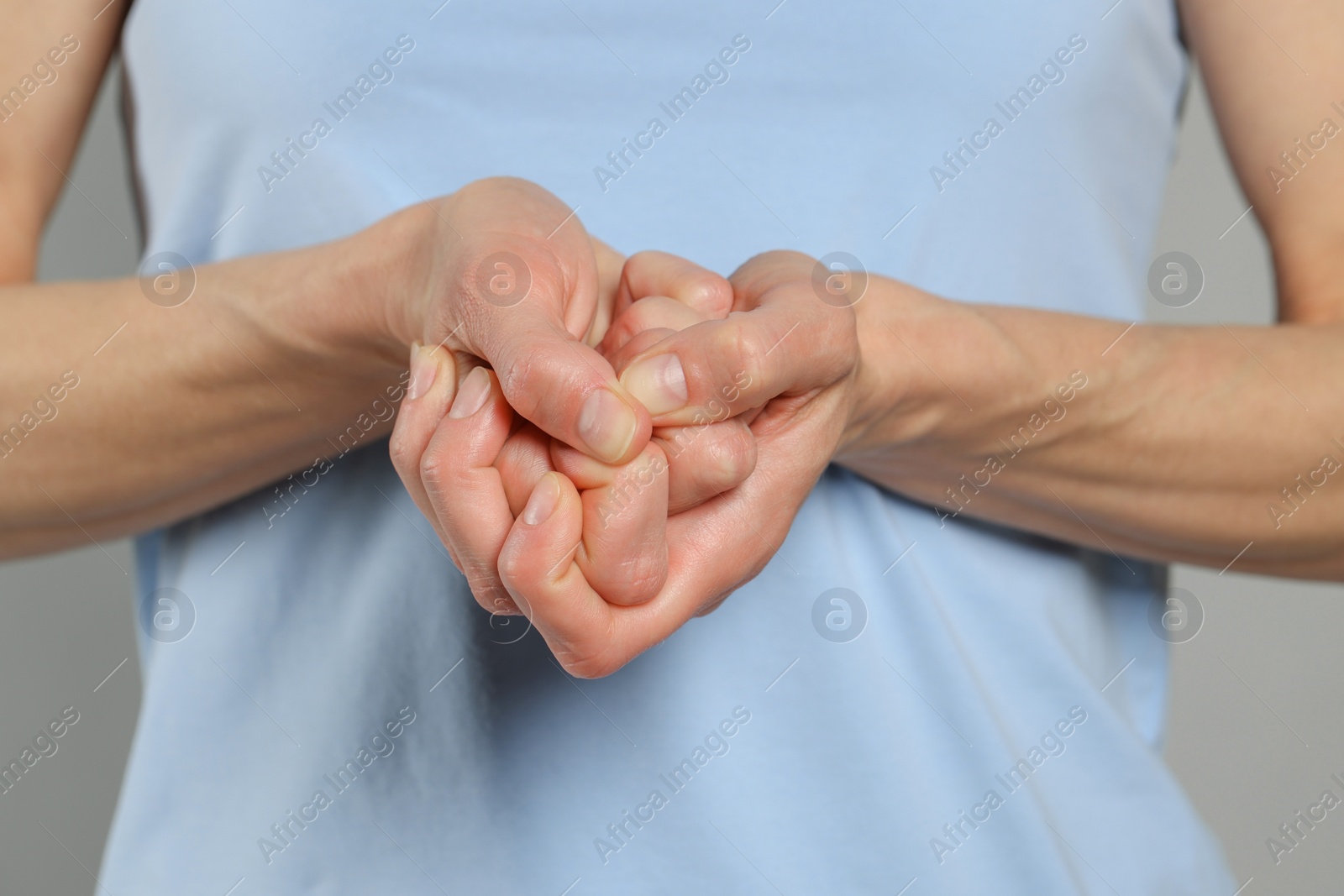 Photo of Woman cracking her knuckles on light grey background, closeup. Bad habit