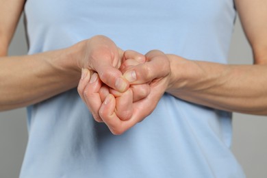 Woman cracking her knuckles on light grey background, closeup. Bad habit