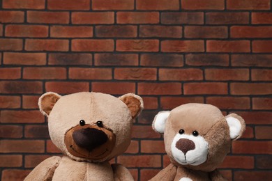 Photo of Cute teddy bears against brick wall. Space for text